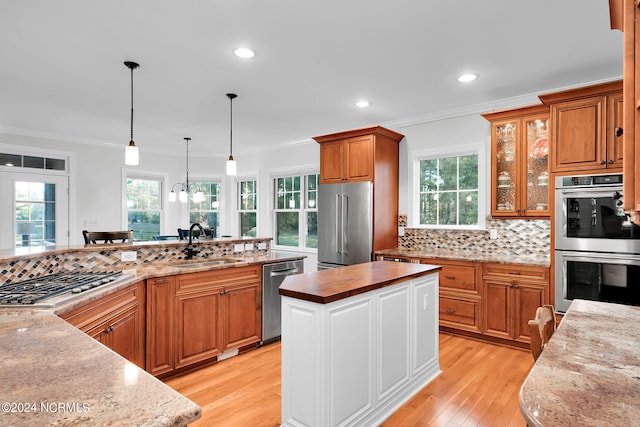 kitchen featuring a center island, backsplash, stainless steel appliances, pendant lighting, and a wealth of natural light