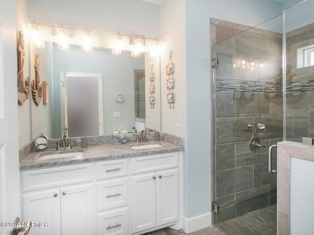 full bath with a stall shower, a sink, and double vanity