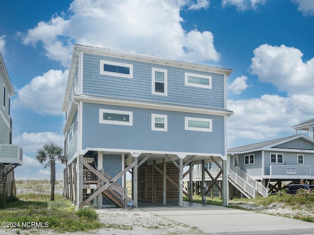 beach home with stairway, a carport, and concrete driveway