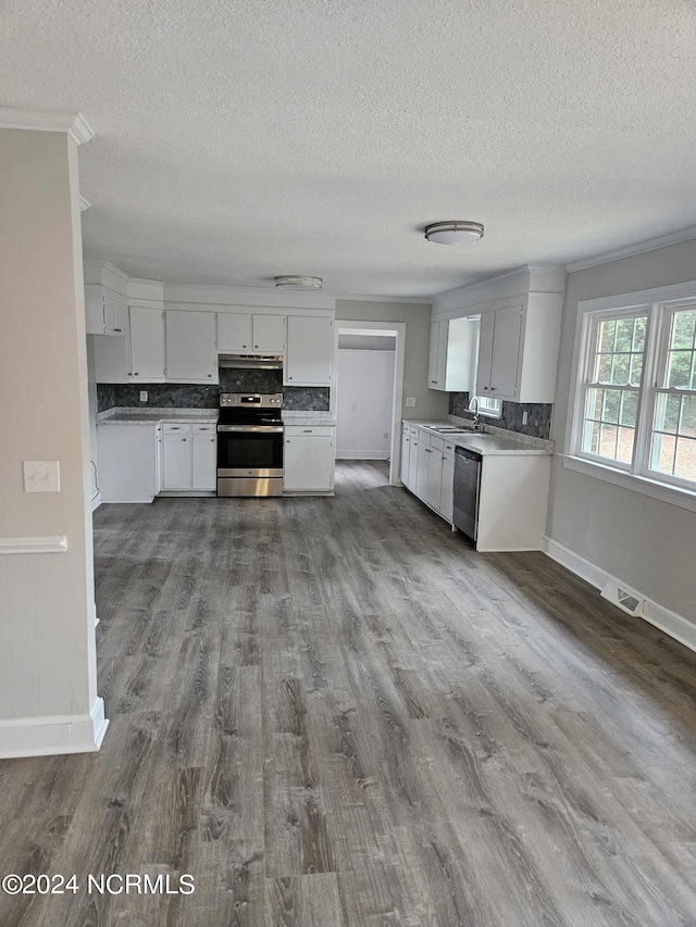 kitchen featuring wood-type flooring, stainless steel appliances, ornamental molding, and white cabinets