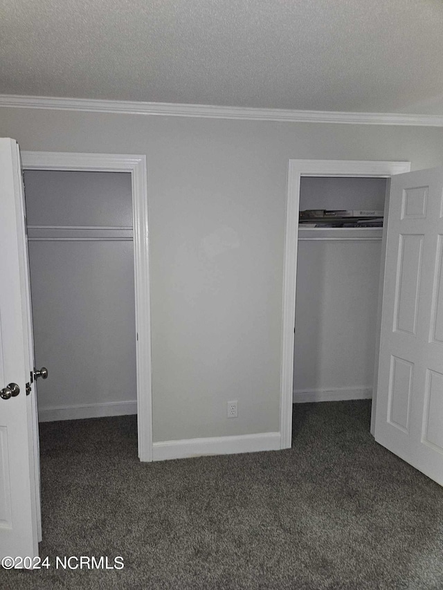 unfurnished bedroom with crown molding, dark carpet, and a textured ceiling