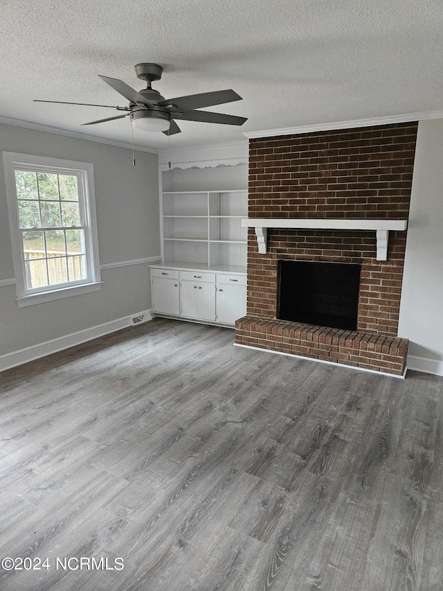 unfurnished living room featuring hardwood / wood-style flooring, a textured ceiling, a brick fireplace, and ceiling fan