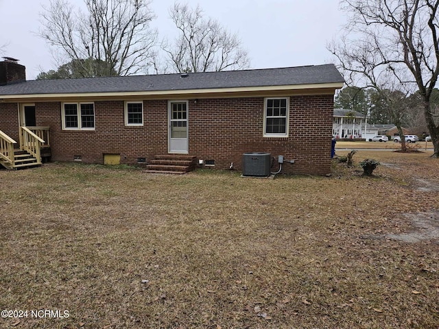 rear view of house featuring cooling unit and a lawn