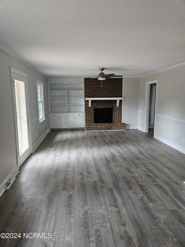 unfurnished living room with crown molding, a brick fireplace, dark hardwood / wood-style floors, and ceiling fan