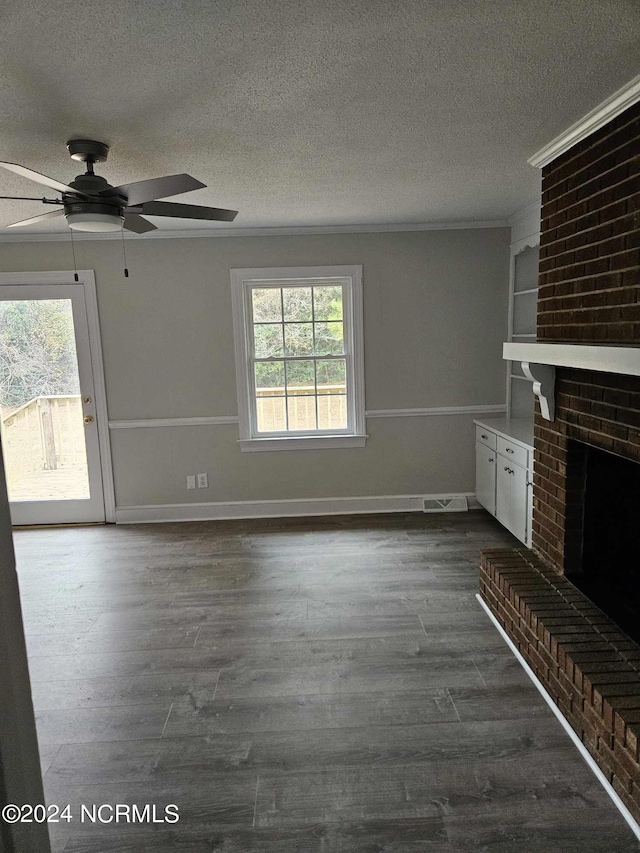 unfurnished living room featuring plenty of natural light, a fireplace, dark wood-type flooring, and ceiling fan