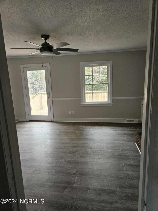 empty room with wood-type flooring, a textured ceiling, ornamental molding, and ceiling fan