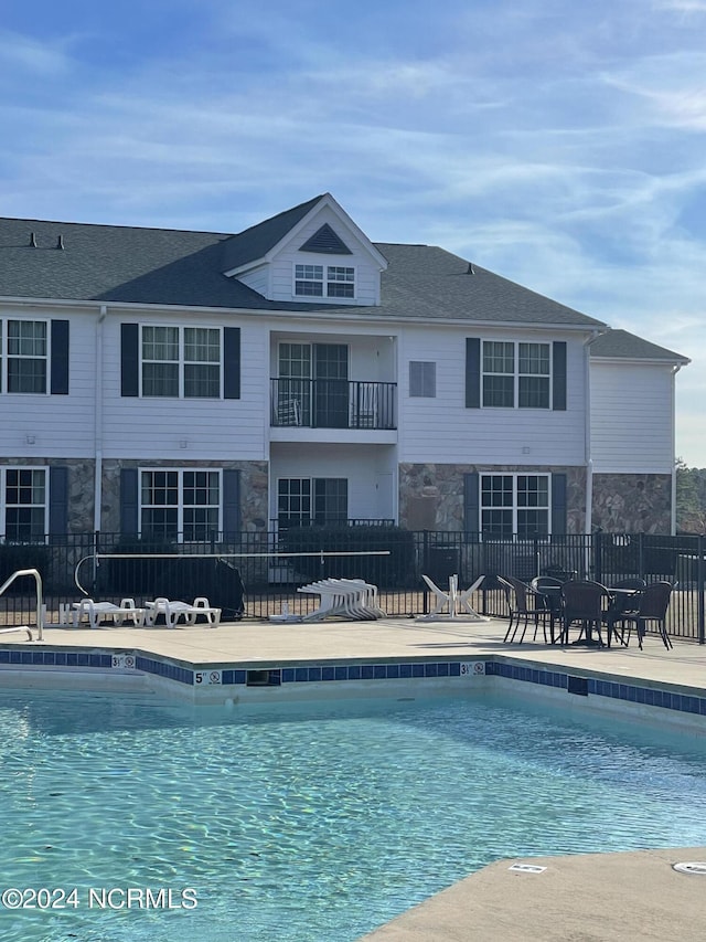 community pool with fence and a patio area