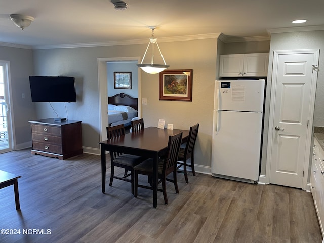 dining space featuring dark wood-type flooring, ornamental molding, and baseboards