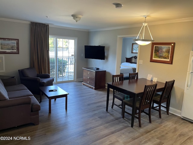dining room with wood finished floors, ornamental molding, and baseboards