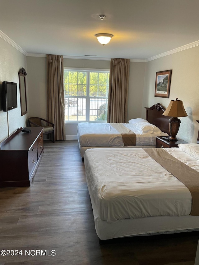 bedroom with crown molding, wood finished floors, and baseboards