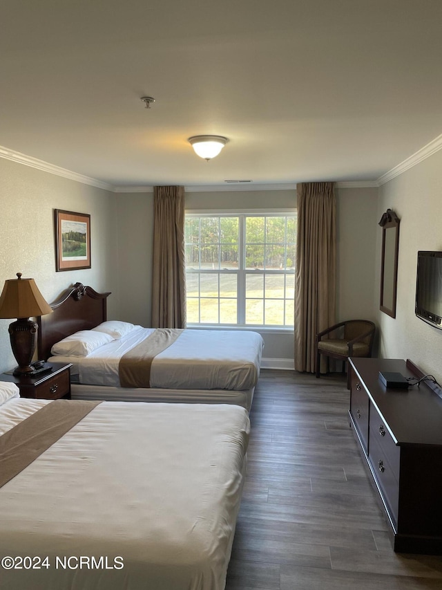 bedroom with crown molding, dark wood-type flooring, and baseboards
