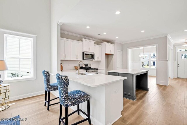 kitchen with kitchen peninsula, sink, appliances with stainless steel finishes, a kitchen breakfast bar, and white cabinets