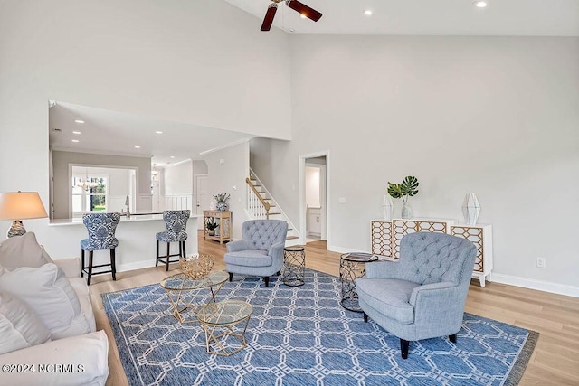 living room featuring ceiling fan, sink, hardwood / wood-style flooring, and a towering ceiling