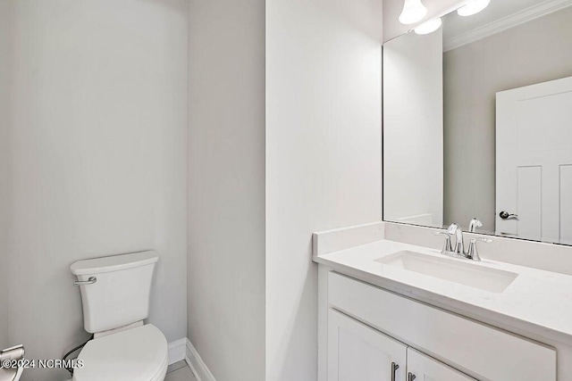 bathroom featuring toilet, vanity, and ornamental molding