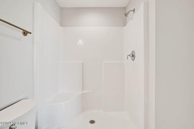 bathroom featuring walk in shower and toilet