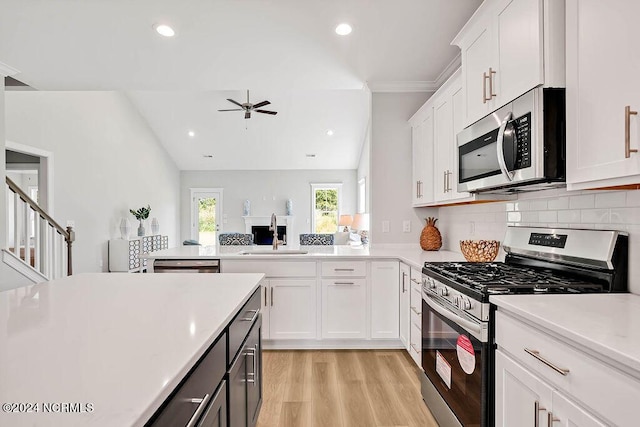 kitchen with appliances with stainless steel finishes, lofted ceiling, white cabinetry, and sink