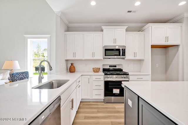 kitchen with stainless steel appliances, backsplash, white cabinets, and sink