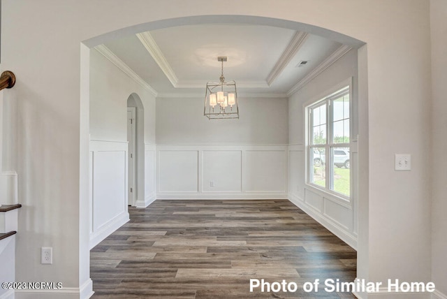 unfurnished dining area featuring dark hardwood / wood-style floors, a tray ceiling, and ornamental molding