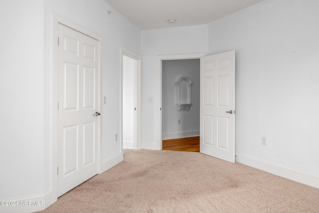 unfurnished bedroom featuring light carpet and a closet