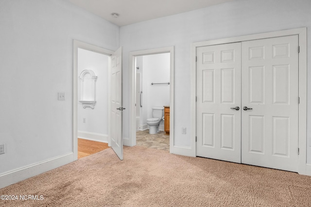 unfurnished bedroom with connected bathroom, a closet, and light carpet