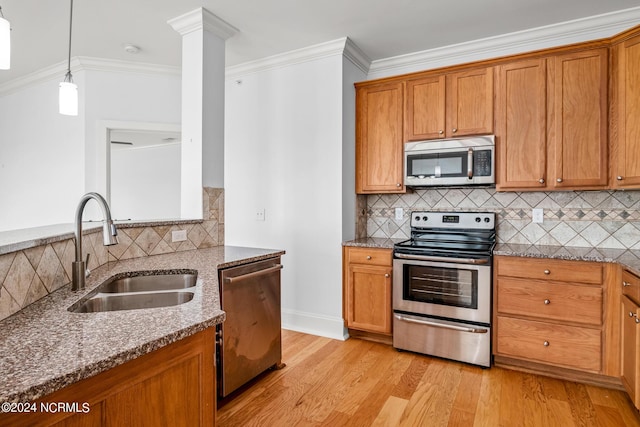 kitchen with crown molding, appliances with stainless steel finishes, sink, light hardwood / wood-style flooring, and stone countertops