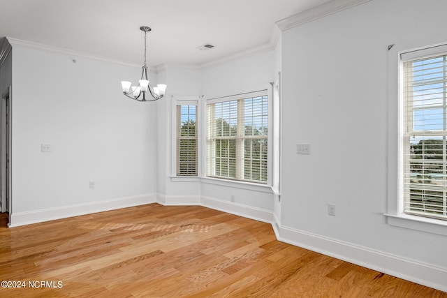 unfurnished dining area with light hardwood / wood-style floors, crown molding, and a chandelier