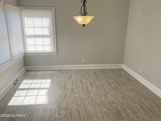 unfurnished dining area with visible vents, baseboards, and wood finished floors