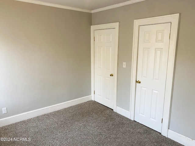 unfurnished bedroom with crown molding, baseboards, and dark colored carpet