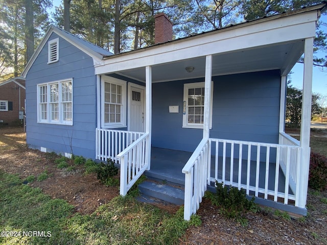 view of front facade with covered porch and a chimney