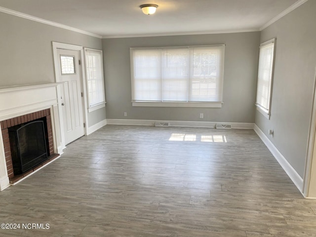 unfurnished living room with wood finished floors, a fireplace, baseboards, and ornamental molding