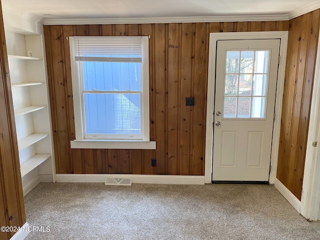 entryway featuring wooden walls, visible vents, crown molding, built in features, and carpet floors