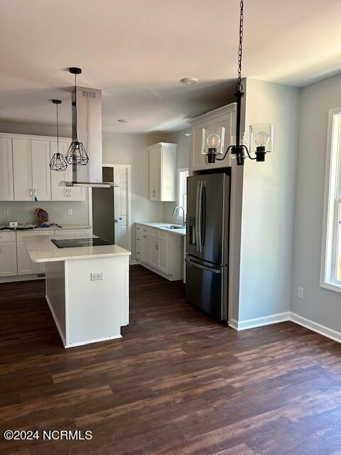 kitchen with white cabinets, stainless steel fridge with ice dispenser, hanging light fixtures, and dark wood-type flooring