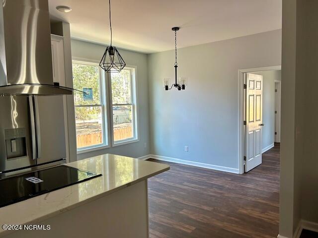 kitchen with wall chimney exhaust hood, hanging light fixtures, stainless steel fridge with ice dispenser, a notable chandelier, and black electric stovetop