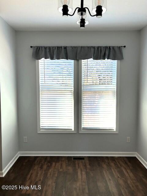 interior space featuring dark wood-type flooring and an inviting chandelier