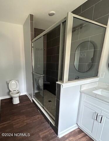 bathroom with hardwood / wood-style floors, vanity, toilet, and walk in shower