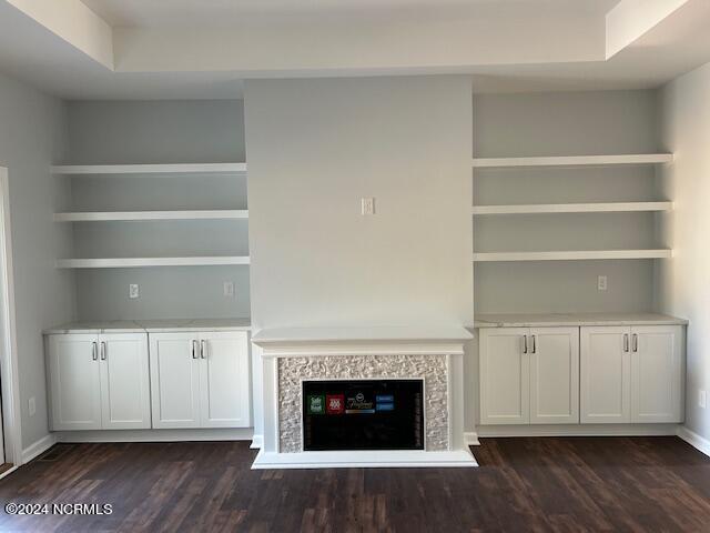 unfurnished living room with built in shelves and dark hardwood / wood-style flooring