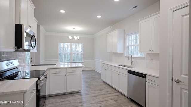 kitchen featuring decorative light fixtures, sink, white cabinets, ornamental molding, and stainless steel appliances