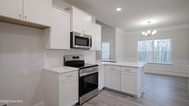 kitchen with white cabinetry, hanging light fixtures, ornamental molding, kitchen peninsula, and stainless steel appliances