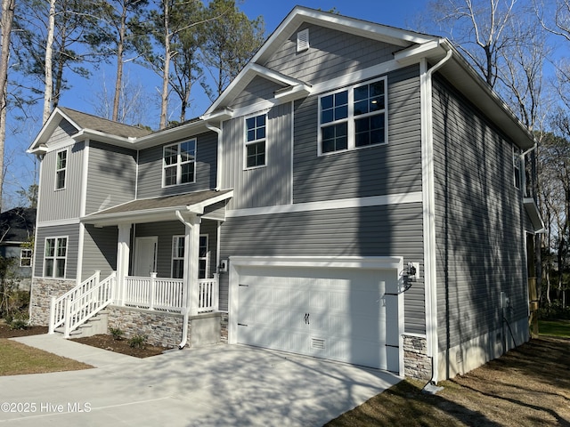 traditional home featuring a porch, stone siding, driveway, and a garage