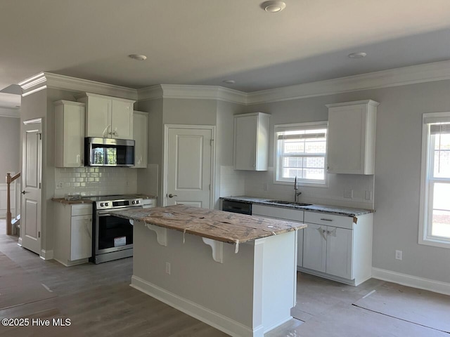 1224 Mandevilla Dr SE, Bolivia, NC 28422 - kitchen with appliances with stainless steel finishes, a sink, a kitchen island, white cabinets, and ornamental molding