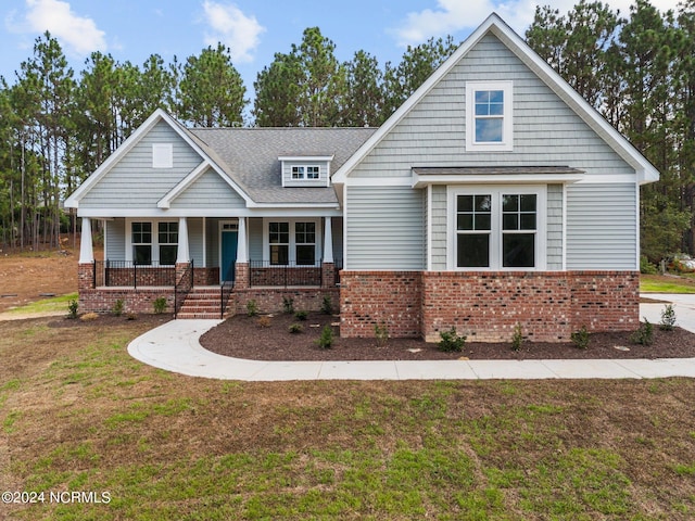 view of front of home featuring a porch, brick siding, and a front lawn