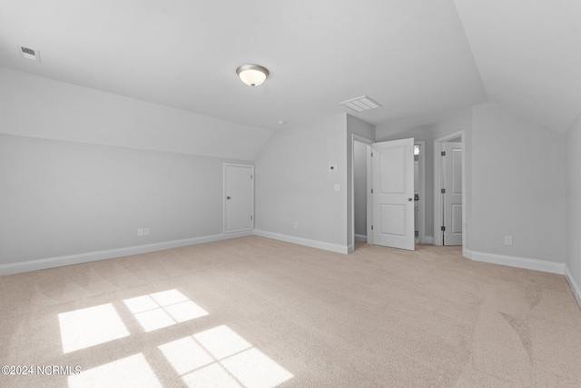 additional living space with lofted ceiling, visible vents, light carpet, and baseboards