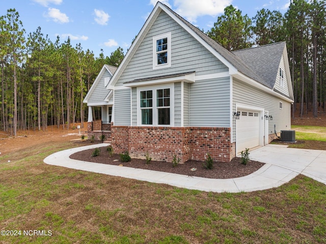 view of front of home with central AC unit, a garage, brick siding, driveway, and a front yard