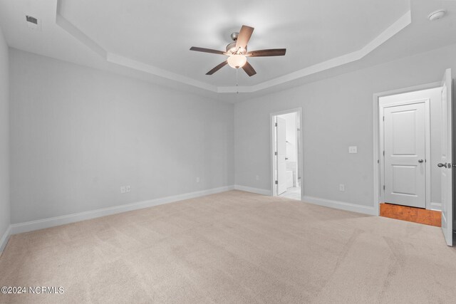 unfurnished room featuring light carpet, a raised ceiling, and ceiling fan