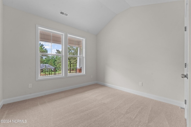 carpeted spare room featuring lofted ceiling, visible vents, and baseboards