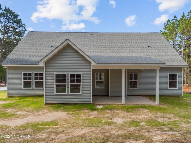 back of property with a patio area and roof with shingles