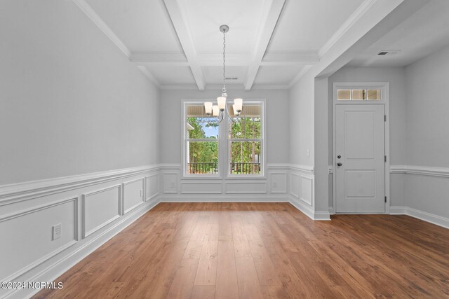 unfurnished dining area with coffered ceiling, beam ceiling, a notable chandelier, and wood-type flooring