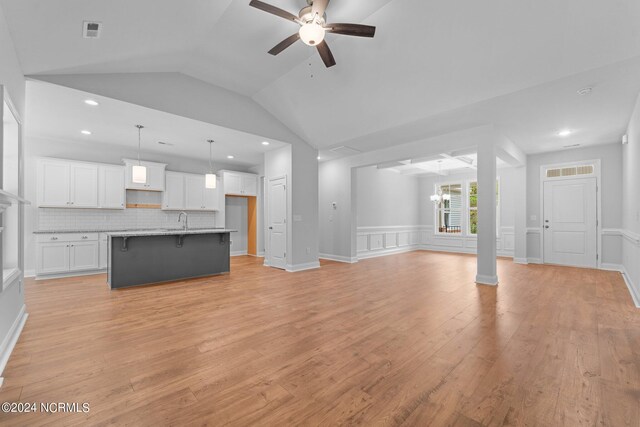 unfurnished living room featuring lofted ceiling, sink, light wood-type flooring, and ceiling fan