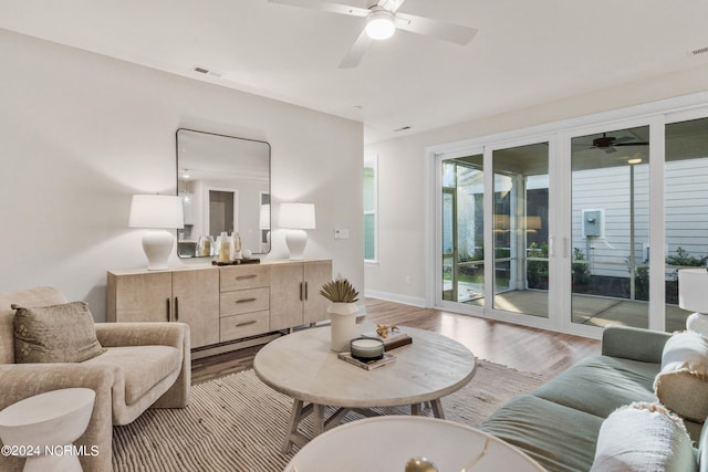 living area with baseboards, visible vents, ceiling fan, and light wood finished floors