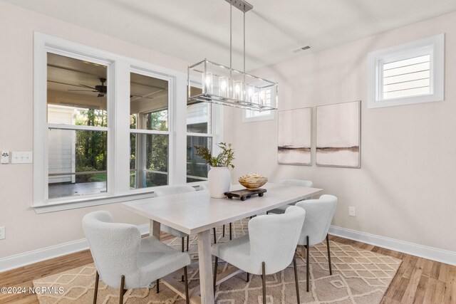 dining area with an inviting chandelier, visible vents, baseboards, and wood finished floors